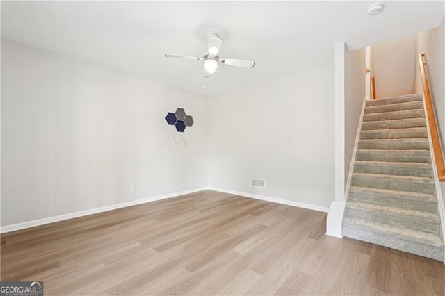 interior space featuring visible vents, baseboards, ceiling fan, wood finished floors, and stairs