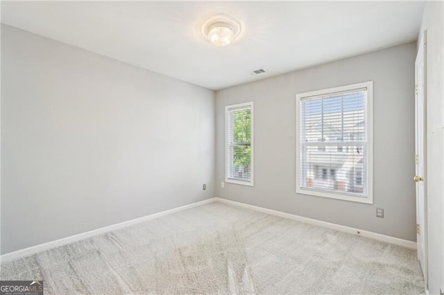 carpeted spare room with visible vents and baseboards