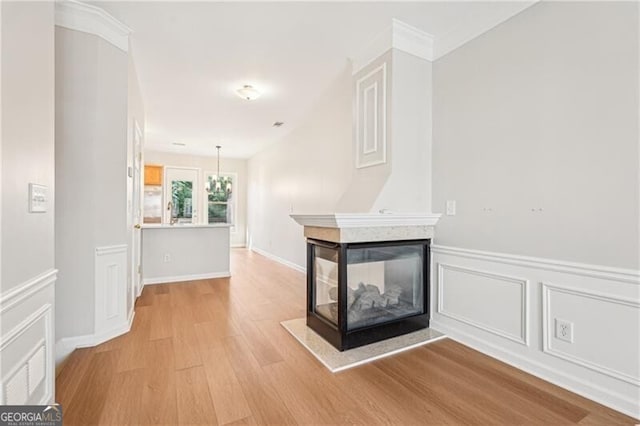 corridor with light wood-style floors, a decorative wall, and wainscoting