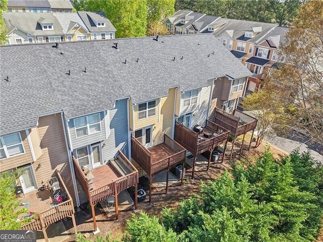 back of house with a residential view, roof with shingles, and a wooden deck