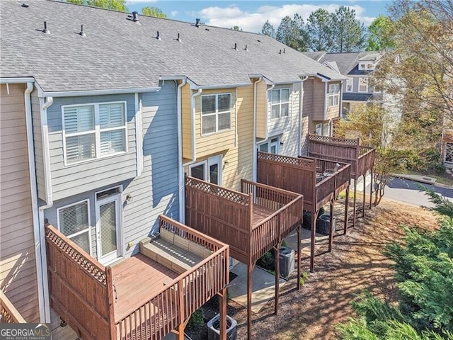 rear view of property featuring roof with shingles, a deck, and central AC