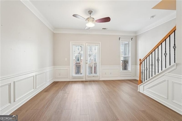 unfurnished living room featuring a decorative wall, stairway, ceiling fan, and wood finished floors