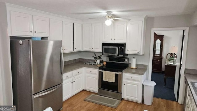kitchen with light wood-style flooring, appliances with stainless steel finishes, a ceiling fan, and white cabinetry