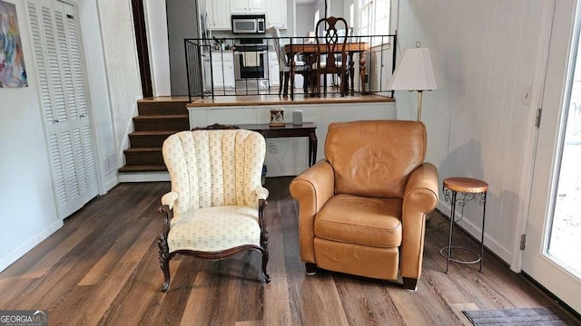 sitting room featuring baseboards, stairway, and wood finished floors
