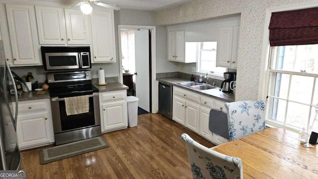 kitchen with stainless steel appliances, dark wood-style floors, white cabinetry, and a sink