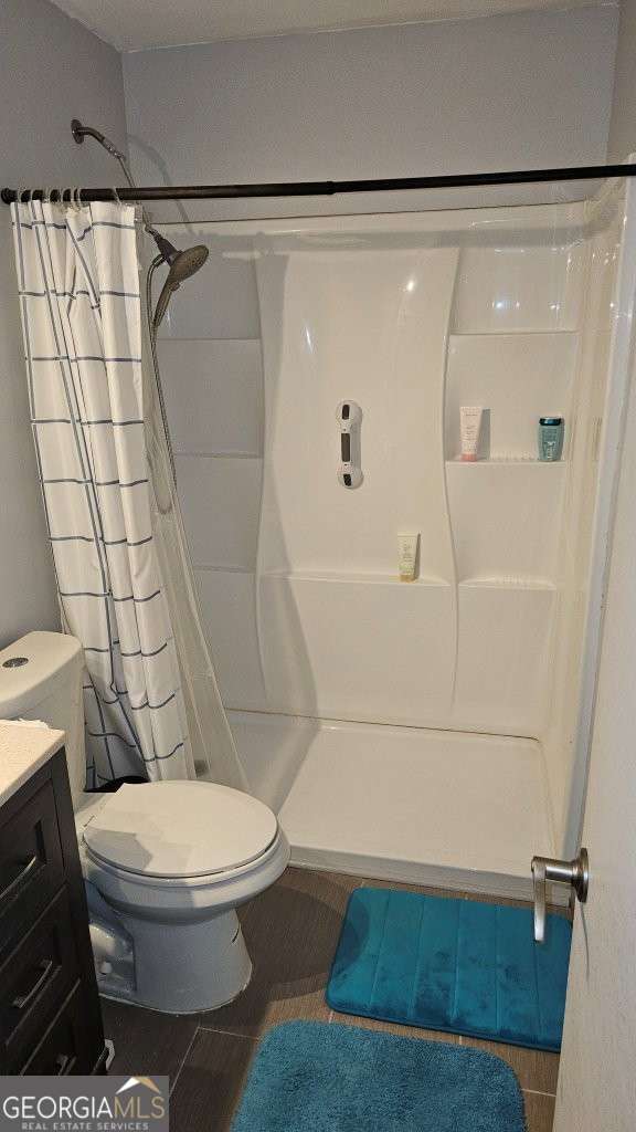 full bathroom featuring toilet, a stall shower, vanity, and tile patterned floors