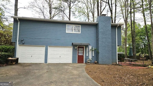 view of front of house featuring a chimney, driveway, and a garage
