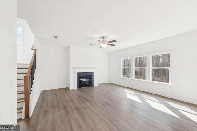 unfurnished living room featuring visible vents, a ceiling fan, wood finished floors, and stairs