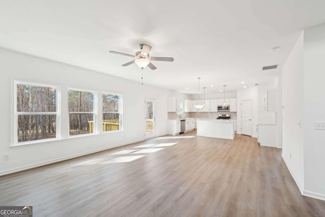 unfurnished living room featuring baseboards, recessed lighting, light wood-style flooring, a ceiling fan, and visible vents