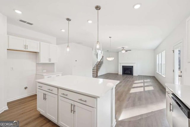 kitchen with visible vents, white cabinets, dishwasher, ceiling fan, and a fireplace