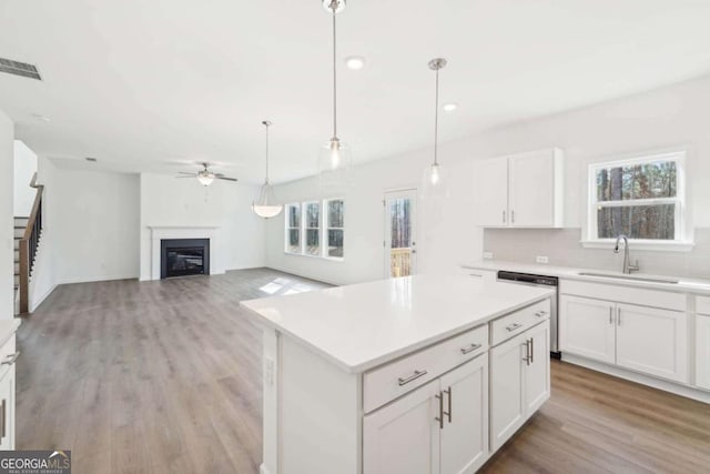 kitchen with visible vents, dishwasher, a sink, a ceiling fan, and light wood finished floors