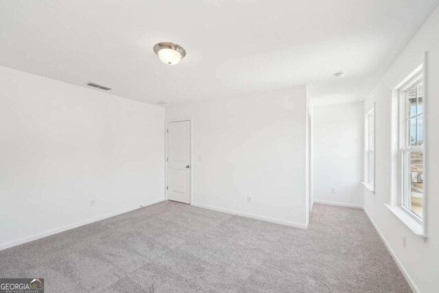 unfurnished room with carpet flooring, baseboards, and visible vents