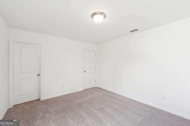 carpeted spare room featuring visible vents and baseboards