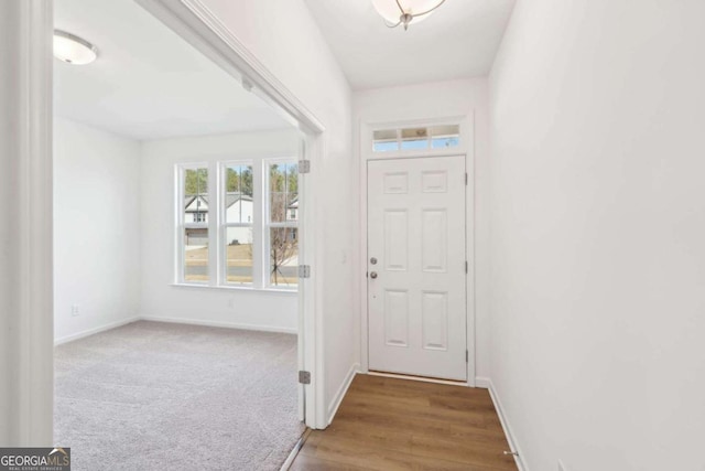 doorway to outside with carpet floors, baseboards, and wood finished floors