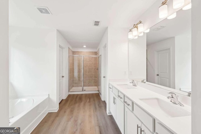 full bath with a stall shower, a bath, visible vents, a sink, and wood finished floors