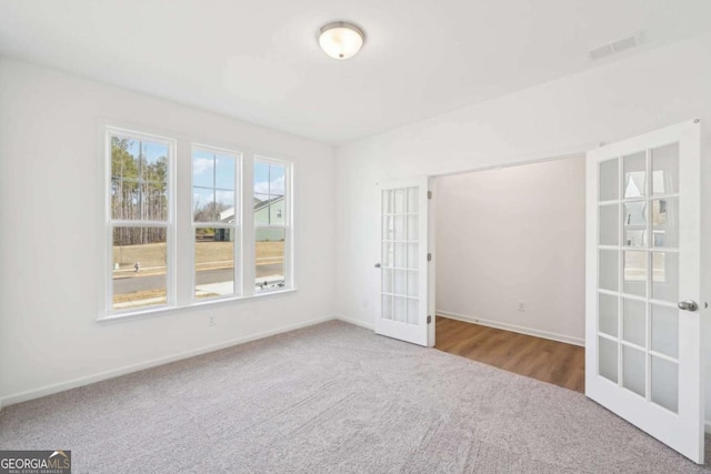 spare room with french doors, baseboards, carpet flooring, and visible vents