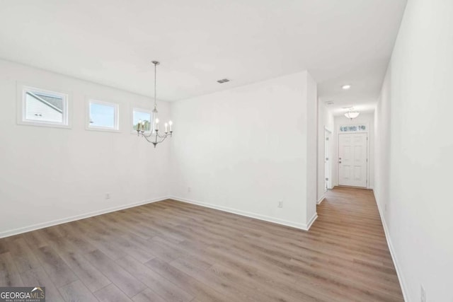 unfurnished dining area with visible vents, baseboards, an inviting chandelier, recessed lighting, and wood finished floors