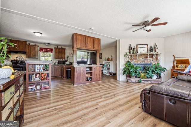 2496 Venture Dr, Gainesville, GA 30506 - living area featuring light wood-type flooring, a ceiling fan, a stone fireplace, and a textured ceiling
