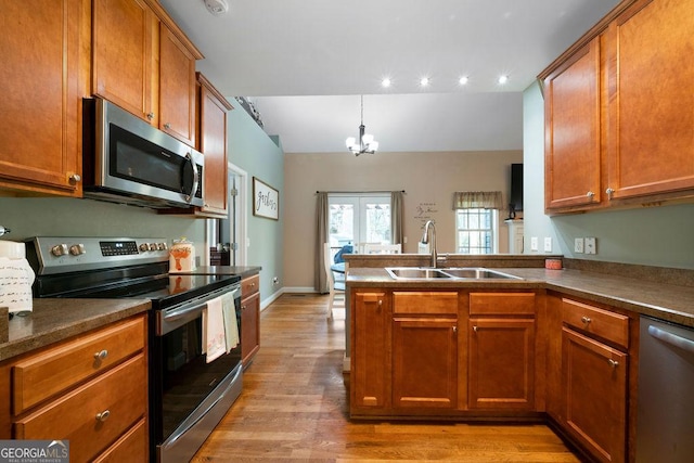 kitchen featuring stainless steel appliances, brown cabinetry, light wood-style floors, and a sink