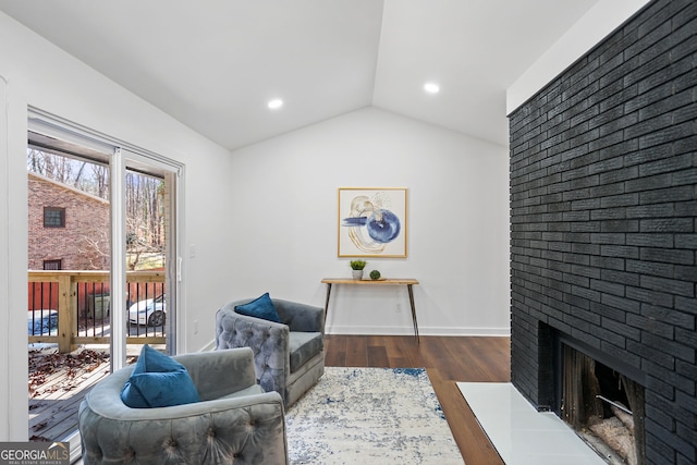 sitting room with a brick fireplace, recessed lighting, vaulted ceiling, and dark wood-style floors