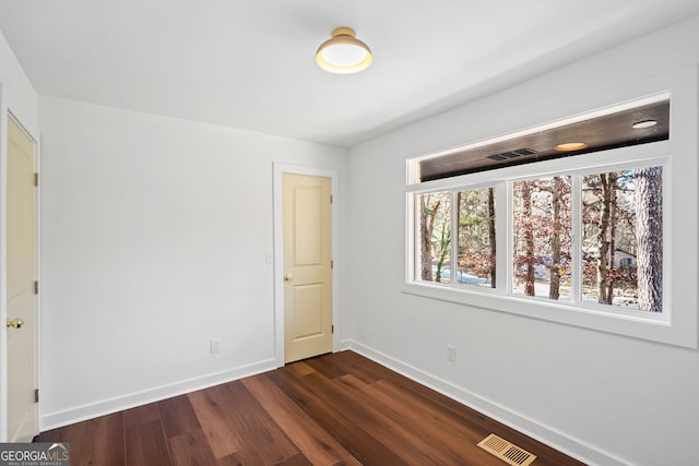 unfurnished bedroom featuring dark wood-type flooring, visible vents, and baseboards