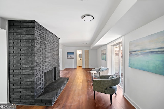 living room featuring a fireplace, wood-type flooring, and baseboards