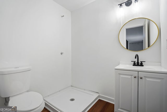 bathroom with baseboards, toilet, a shower, vanity, and wood finished floors