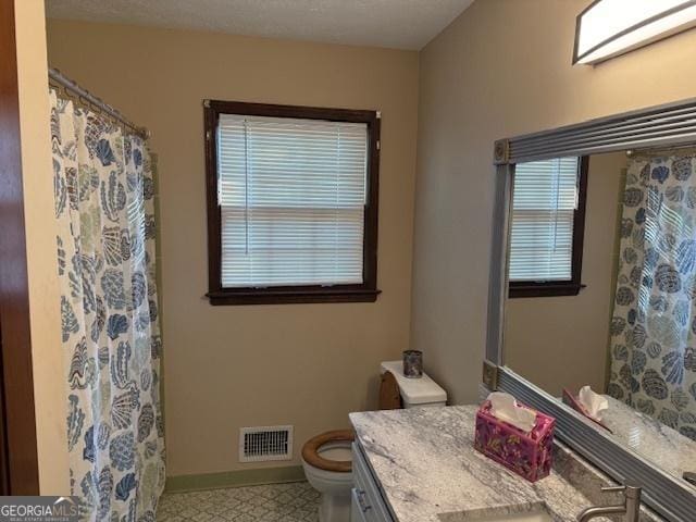 full bath featuring vanity, visible vents, toilet, a shower with shower curtain, and baseboards