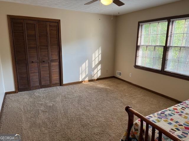 carpeted bedroom featuring visible vents, baseboards, a closet, and ceiling fan