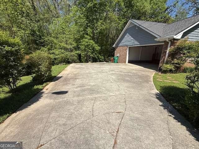view of property exterior featuring an attached garage, driveway, and brick siding