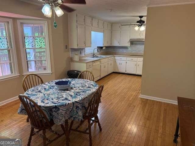 kitchen with baseboards, light wood-type flooring, light countertops, and a ceiling fan