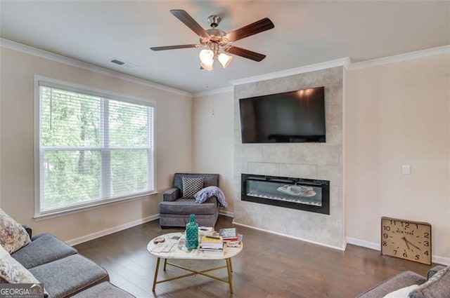 living area featuring crown molding, ceiling fan, a fireplace, visible vents, and wood finished floors