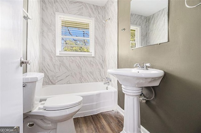 bathroom with plenty of natural light, shower / bathtub combination, toilet, and wood finished floors