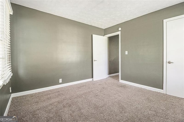unfurnished bedroom with a textured ceiling, baseboards, and carpet