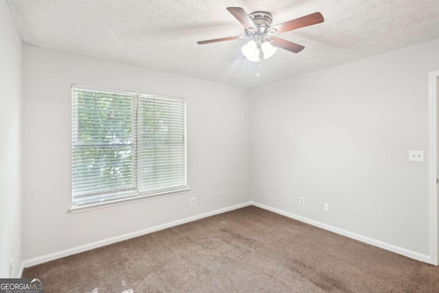 carpeted empty room with baseboards, a ceiling fan, and a textured ceiling
