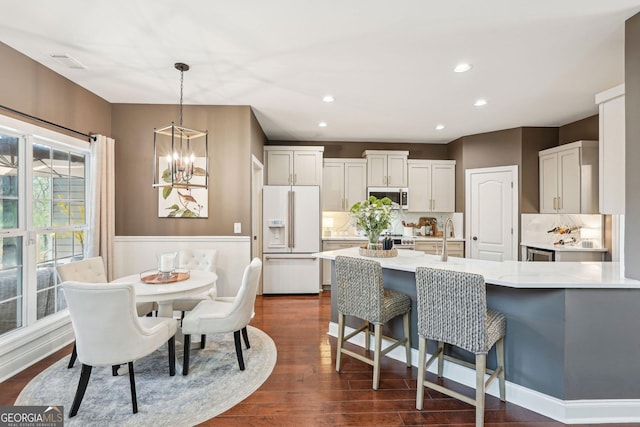 185 Starlight Dr, Dahlonega, GA 30533 - kitchen featuring dark wood finished floors, white refrigerator with ice dispenser, stainless steel microwave, a breakfast bar area, and a notable chandelier