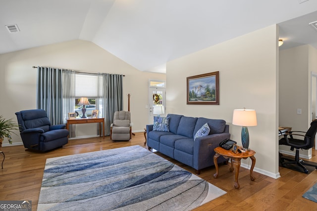 living room featuring wood finished floors, baseboards, lofted ceiling, and visible vents