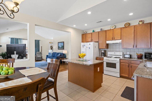 kitchen featuring white appliances, a kitchen island, under cabinet range hood, visible vents, and lofted ceiling