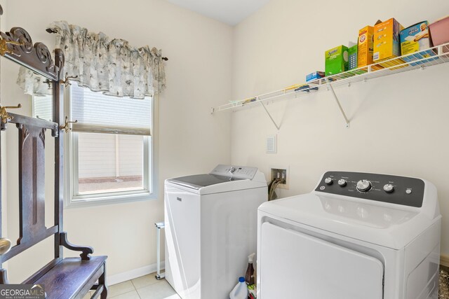 laundry area with light tile patterned floors, washing machine and clothes dryer, laundry area, and baseboards
