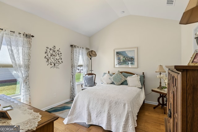 bedroom with visible vents, baseboards, wood finished floors, and vaulted ceiling