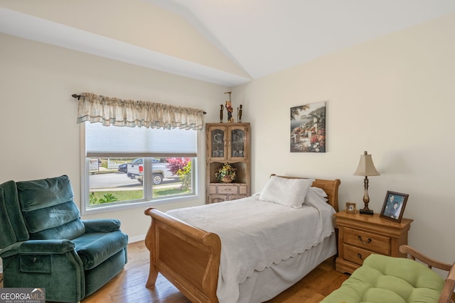 bedroom featuring light wood-style floors, baseboards, and vaulted ceiling