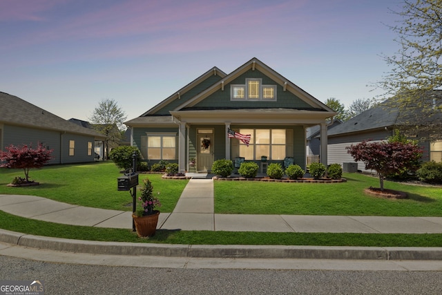 craftsman-style home featuring central air condition unit, a lawn, and covered porch