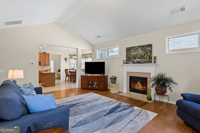living area with visible vents, light wood-style floors, and lofted ceiling