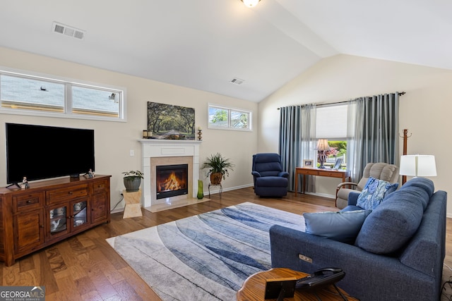 living room with a fireplace with flush hearth, visible vents, wood finished floors, and lofted ceiling