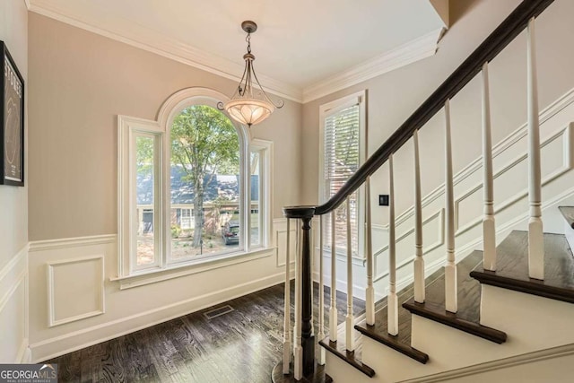 stairway with wood finished floors, a decorative wall, ornamental molding, and a wainscoted wall