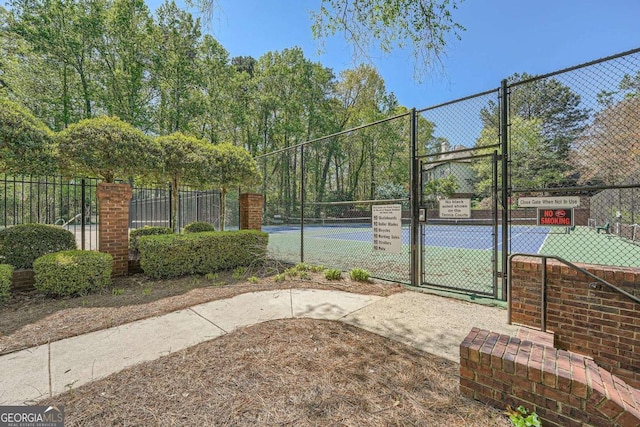 view of tennis court featuring fence and a gate