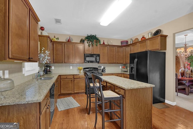 2384 Allsborough Way, Dacula, GA 30019 - kitchen with black appliances, a sink, light wood finished floors, a center island, and brown cabinetry