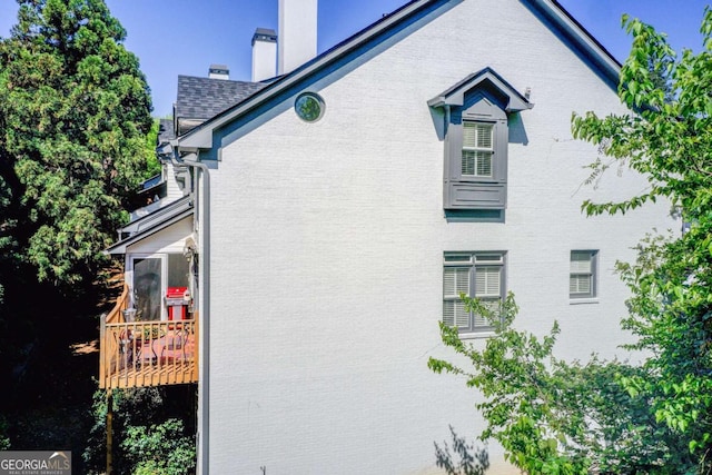 view of property exterior featuring a chimney and brick siding