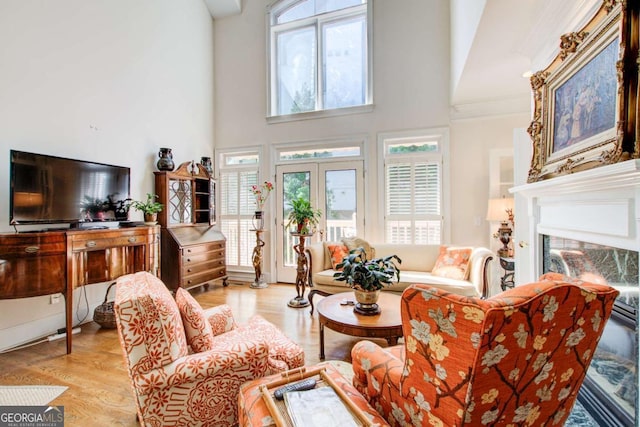 living room with a wealth of natural light, a towering ceiling, and light wood-type flooring