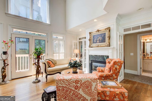living room with a high end fireplace, baseboards, ornamental molding, and wood finished floors